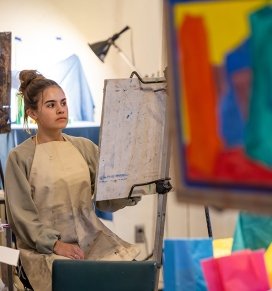 A student works on a work of art in painting class