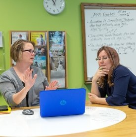 English professor Stephanie Drotos works with a student at a desk in class