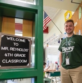 Image of Travis Reynolds standing in front of his 4th grade classrooms at Hudson Falls Primary School