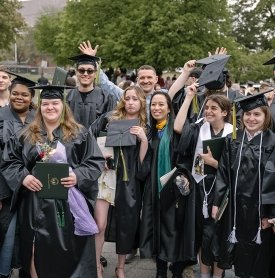 A group of graduates celebrates outside Cool Insuring Arena after commencement 2024