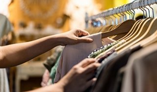 A person looks through blouses hanging on a rack