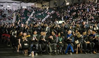 The audience cheers as graduates throw their caps in the air at commencement 2024