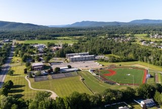 Aerial image of the Queensbury campus with the turf field as the main focus and mountains in the distance