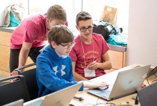 Three students look at a computer screen during a high school event at SUNY Adirondack