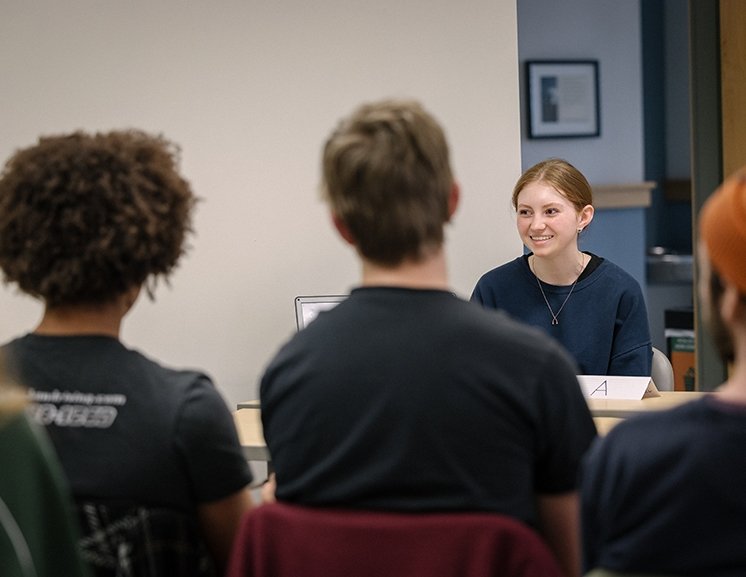 A student smiles as she presents in an English course